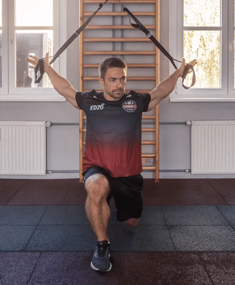 Edző TRX-szel a bordásfal előtt a Forma 1 Fitnesz funkcionális terében
